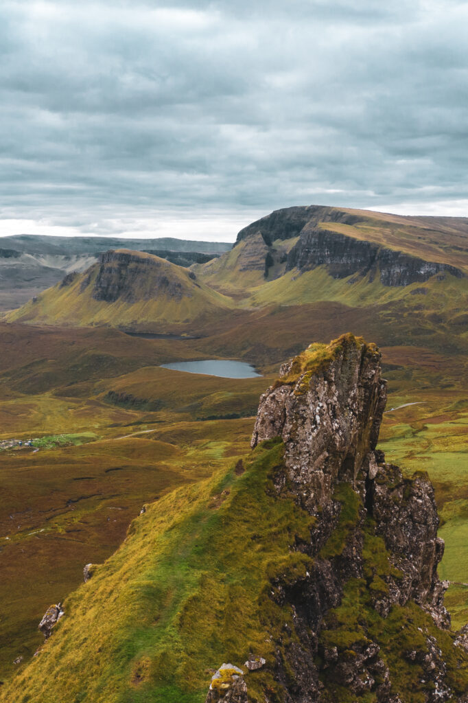 Aerial view of the Quiraing, Isle of Skye, Scotland — dramatic highland landscape with rocky pinnacles, green moorland and a loch under stormy skies