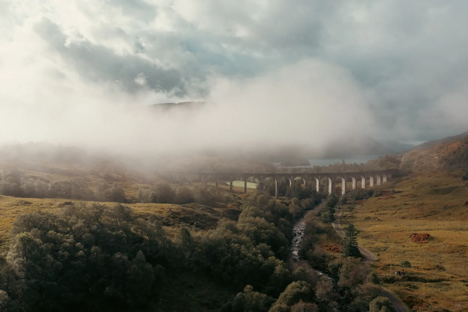 Aerial drone shot of Glenfinnan Viaduct emerging through low cloud and mist, Scottish Highlands — cinematic landscape photography by OV Production